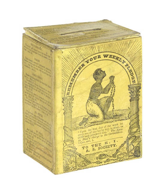 Yellow cardboard box with black print, with a kneeling enslaved figure surrounded by implements of bondage on the front. The top has a slot for coins.