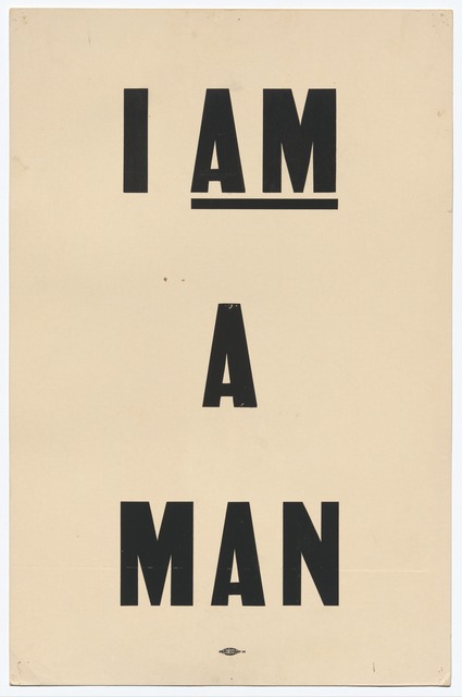 A white poster with black lettering that reads "I AM A MAN."