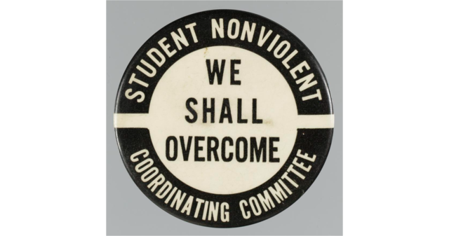 A round, black pinback button with white center. The button text reads, “WE SHALL OVERCOME” and “STUDENT NONVIOLENT COORDINATING COMMITTEE.”